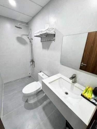a white bathroom with a toilet and a sink at THANH THỦY HoTel in Hà Tiên