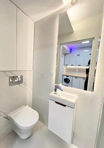 a white bathroom with a toilet and a sink at Lubicz Dolny, A1 Apartament 2 pokojowy in Lubicz