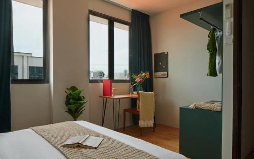 a bedroom with a bed and a desk and windows at House Rong in Singapore