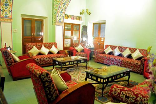 a living room with red couches and tables at Haveli Kalwara - A Heritage Hotel in Jaipur