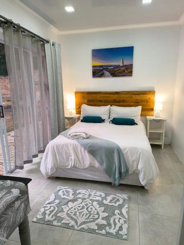 a bedroom with a large bed with white sheets and blue pillows at Wag-n-Bietjie in Centurion