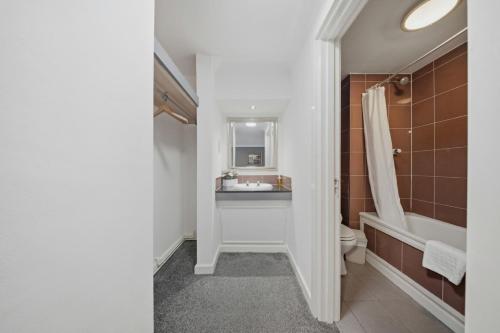 a bathroom with a sink and a toilet and a tub at The Greyhound Hotel in Leigh