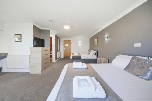 a bedroom with a large white bed and a television at The Greyhound Hotel in Leigh
