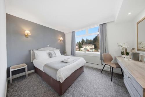 a hotel room with a bed and a desk and a window at The Greyhound Hotel in Leigh