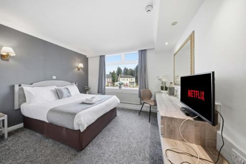 a hotel room with a bed and a tv at The Greyhound Hotel in Leigh