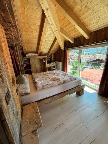 a large bed in a room with a large window at Cuore Tana dell'Orso in Campitello di Fassa