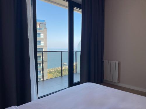 a bedroom with a bed and a large window at Mira Seaview Studio Apartment in Batumi in Batumi