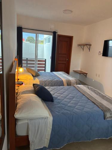 a bedroom with two beds and a television and a window at KC Suites in Comitán