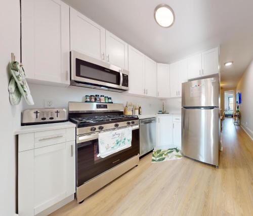 a kitchen with white cabinets and a stainless steel refrigerator at Garden Street Retreat - 15 Minutes to NYC in Hoboken