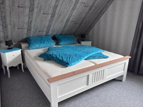 a white bed with blue pillows on it at FeWo Fuhrmann in Bensersiel