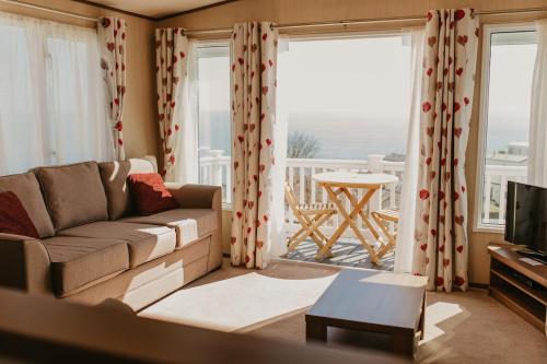 a living room with a couch and a table and windows at Upper Cliff 2 in Easton