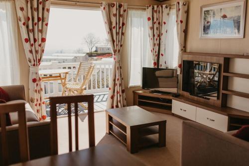 a living room with a television and a balcony at Upper Cliff 2 in Easton