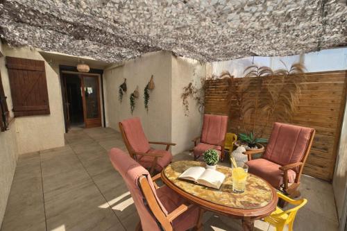 a patio with a wooden table and chairs and a table at Maison classée 3étoiles proche plage in Mauguio