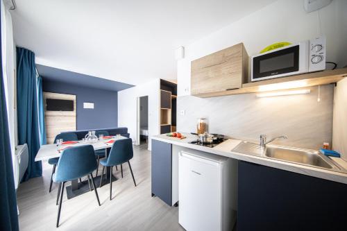 a kitchen with a sink and a table with chairs at City Résidence Nancy in Nancy