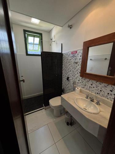 a bathroom with a sink and a toilet and a mirror at Pousada Solar dos Guarás in Catas Altas