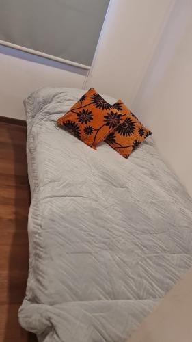 a white bed with an orange pillow on it at Cabañas Bio Bio Osorno in Osorno