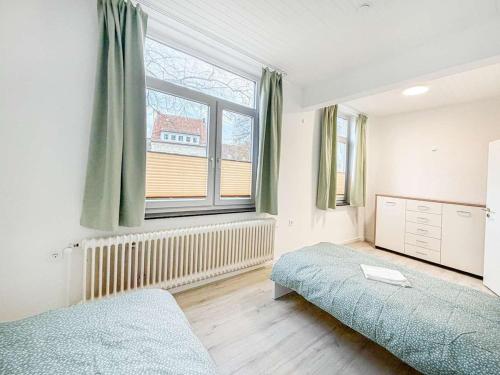 a bedroom with two beds and a large window at Emmas FEWO in Bremen