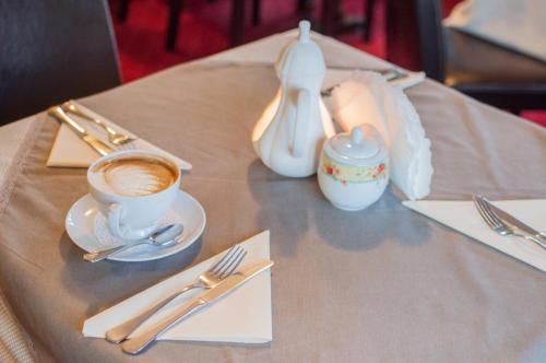 a table topped with a cup of coffee and silverware at Hotel Rypsówka in Nowy Sącz