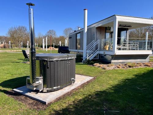 a house with a trash can in the grass at Maasparcje Lodge met Hottub,Firepit en KamadoBBQ in Roermond
