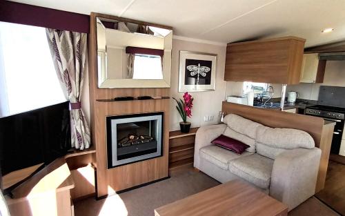 a living room with a couch and a fireplace in a caravan at Bordeaux, Home From Home, Church Farm in Pagham