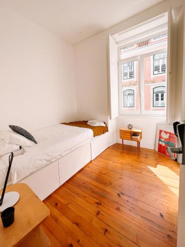 a white bedroom with a bed and a window at samesame living in Lisbon