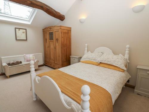 a bedroom with a white bed and a wooden cabinet at Barley Cote Farm in Keighley