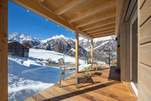 a patio with a table and chairs on a deck with snow covered mountains at Tiny Barrhorn in Grächen