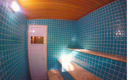 a blue tiled bathroom with a light on a shelf at Pousada Bocaina in São Pedro da Serra