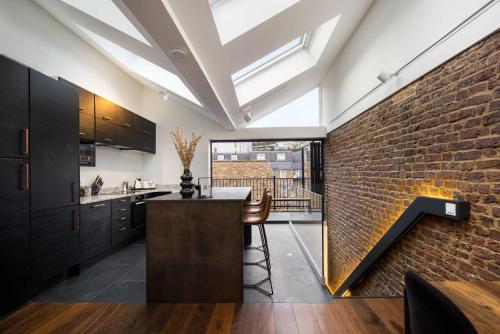 a kitchen with a brick wall and a kitchen island at 1 Min Walk to Euston Station, Modern Townhouse in London