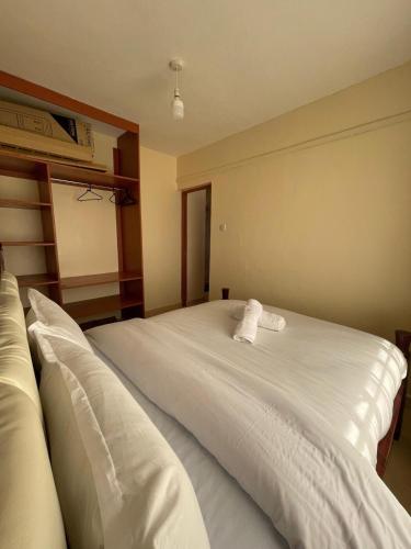 a bedroom with a large white bed with two pillows at Cosy Loft Eldoret in Eldoret