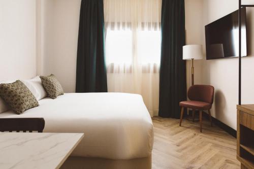 a hotel room with a bed and a chair at Honest Granada Apartments in Granada