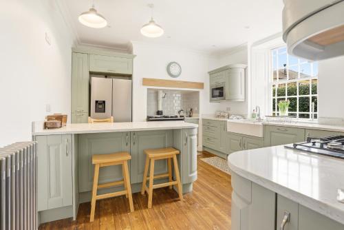 a kitchen with green cabinets and two bar stools at Lantern House - North East Escapes in Belford