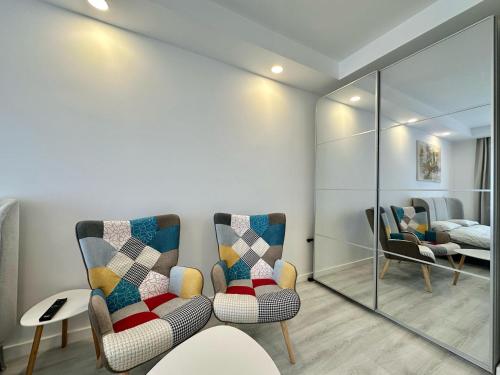a living room with two chairs and a mirror at Anturium Studio #Otopeni #freePool in Tunari