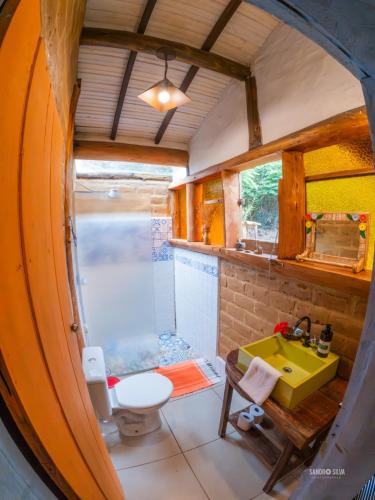 a bathroom with a shower and a yellow sink at Pousada Villa Cachoeira in Carrancas