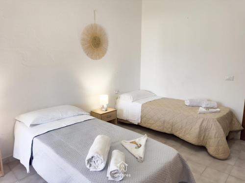 two beds in a white room with towels on them at Residenza Centrale in Villasimius