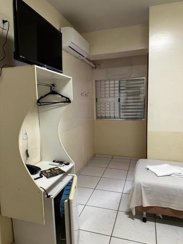 a small room with a bed and a flat screen tv at Hotel Realeza in Goiânia