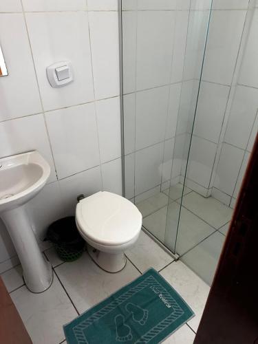 a bathroom with a toilet and a shower and a rug at Hotel Realeza in Goiânia