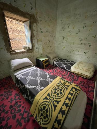 a bedroom with two beds and a window at Merzouga Hostel in Merzouga