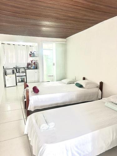 a bedroom with three beds and a kitchen at Edifício AES Brasil in Cairu