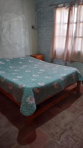 a bedroom with a bed with a blue comforter and a window at Departamento Rincon de Paz in Colón