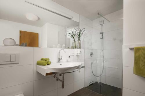 a white bathroom with a sink and a shower at Appartements Veronika in Silbertal