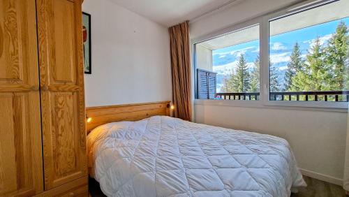 a bedroom with a bed and a large window at Residence les Pleiades in Flaine