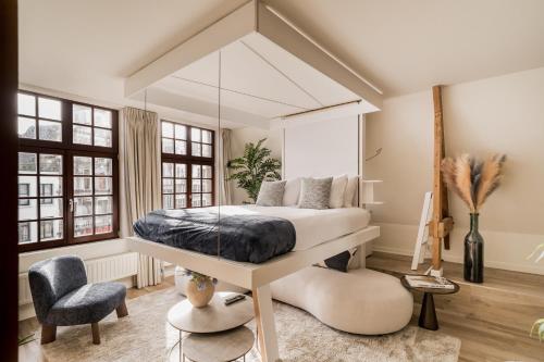 a bedroom with a bed and a chair at Heritage Suites Antwerp in Antwerp