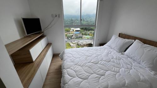 a white bedroom with a bed and a window at Posada del Quindío 0812 in Armenia