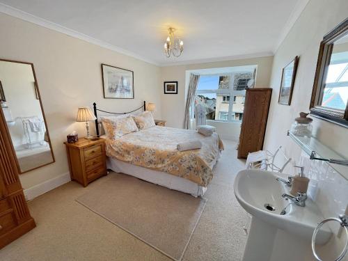 a bedroom with a bed and a sink and a mirror at Pips Corner Lynton in Lynton