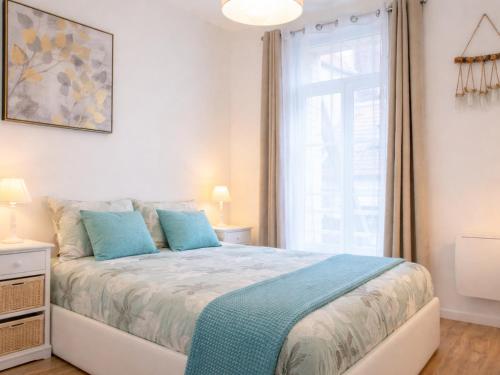 a bedroom with a bed with blue pillows and a window at Le Spacieux à Saint-Omer - 2 chambres, centre et gare à pied, parking privé gratuit in Saint-Omer