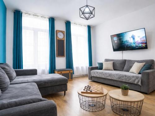 a living room with two couches and a tv at Le Spacieux à Saint-Omer - 2 chambres, centre et gare à pied, parking privé gratuit in Saint-Omer