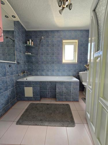 a blue tiled bathroom with a tub and a sink at Власний будинок in Rakhiv
