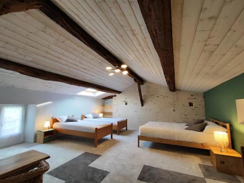 a large room with two beds and a wooden ceiling at L'Orée du Puy in Les Herbiers