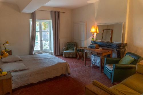 a bedroom with a bed and a table and a fireplace at Manoir de Pincelu in La Courbe
